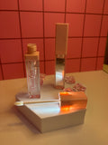 Diva Shine clear lip gloss by Diva's Love Cosmetics, open with applicator displayed on white platform with mirror