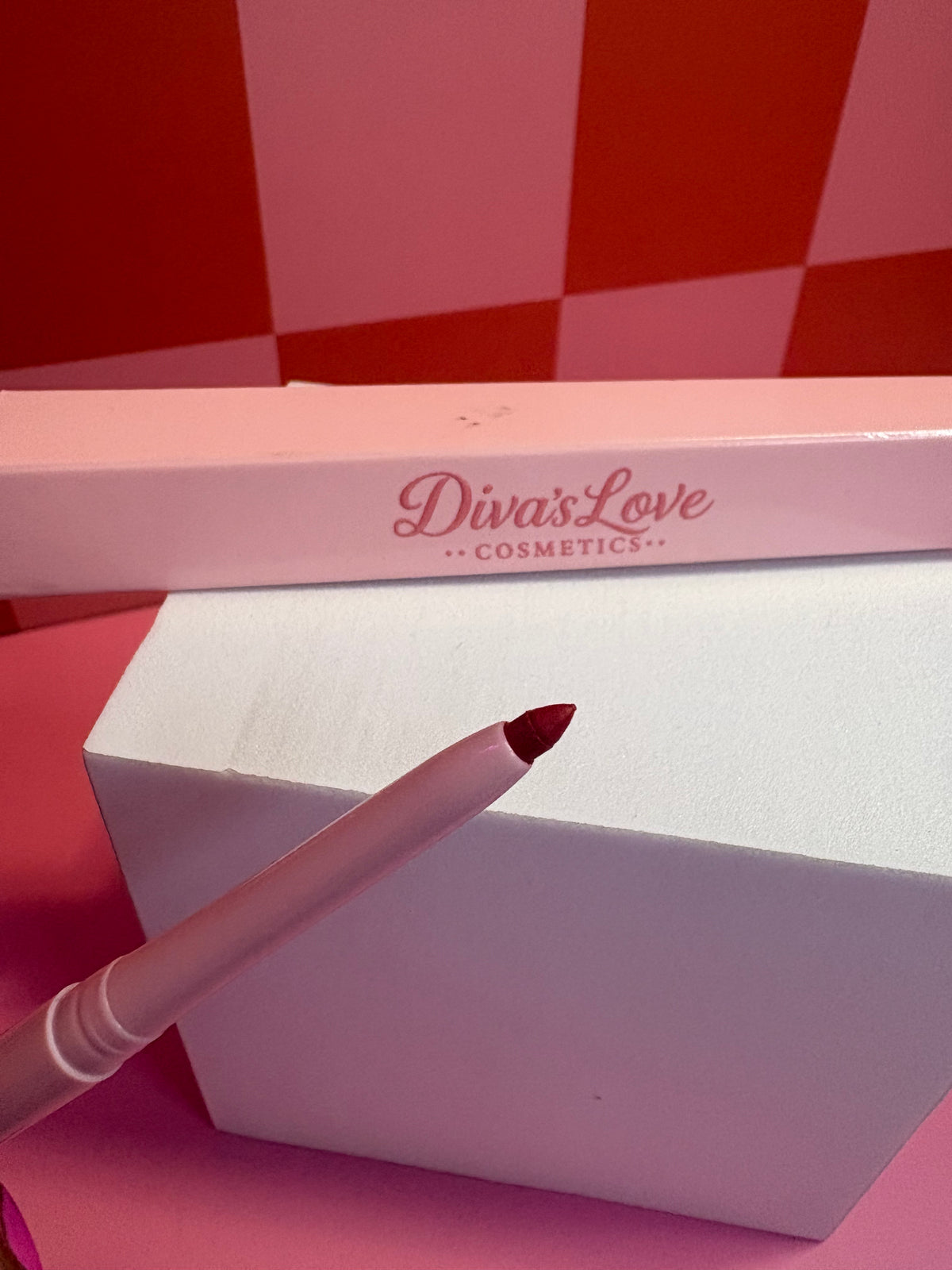 Diva's Love Cosmetics red lip liner with pink packaging on pink checkered background