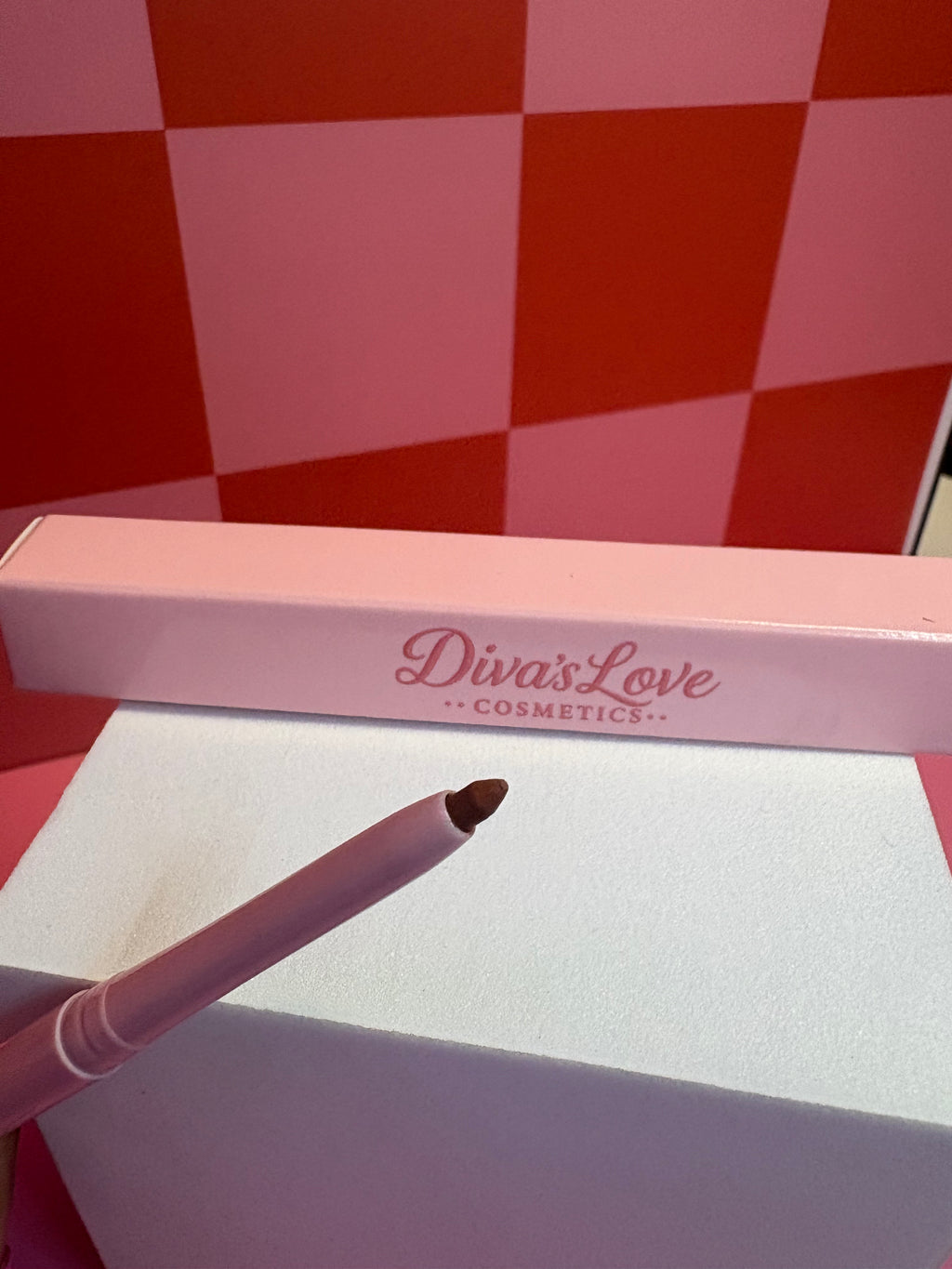Diva's Love Cosmetics brown lip liner with pink packaging on pink checkered background