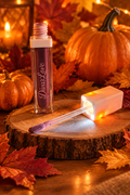 Diva's Plum gloss with illuminated applicator against fall leaves